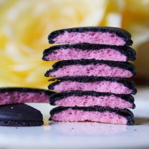 A stack of macarons that are black on the outside and pink inside.