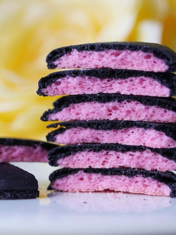 A stack of macarons that are black on the outside and pink inside.