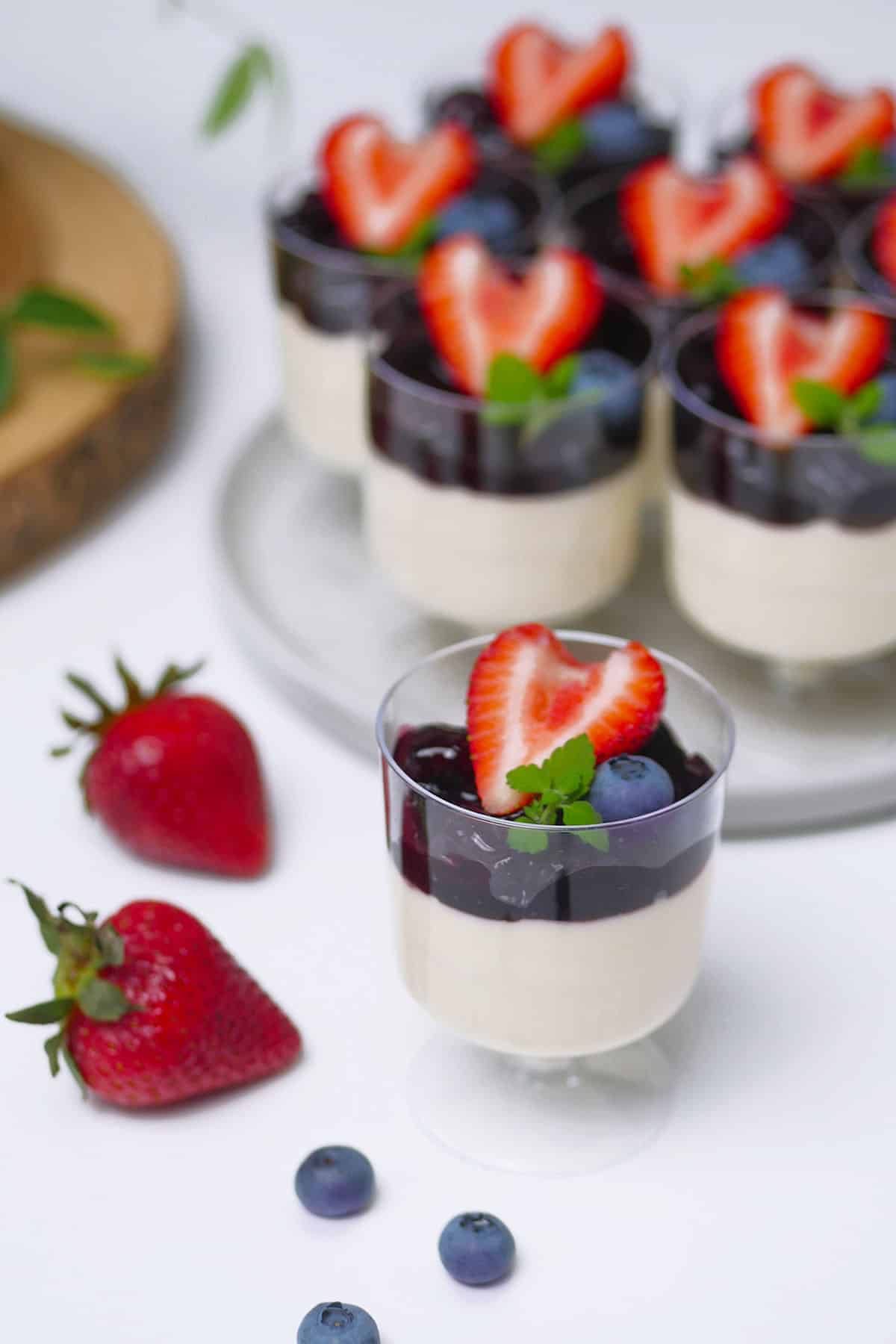 Close up of a single champagne stem cup filled with panna cotta dessert topped with mixed berry sauce. 