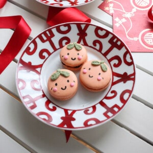 Macarons with cute mandarin faces on a red chinese new years plate.