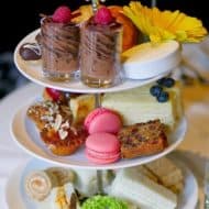 A traditional selection of afternoon tea items on a 3-tier porcelain serving tray.