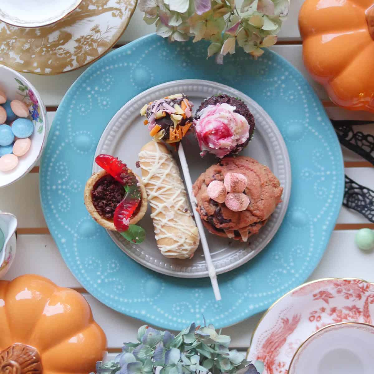 A beautifully arranged dessert plate with assorted sweets, tea, and pumpkins, set for a Tipsy Evening Tea event.