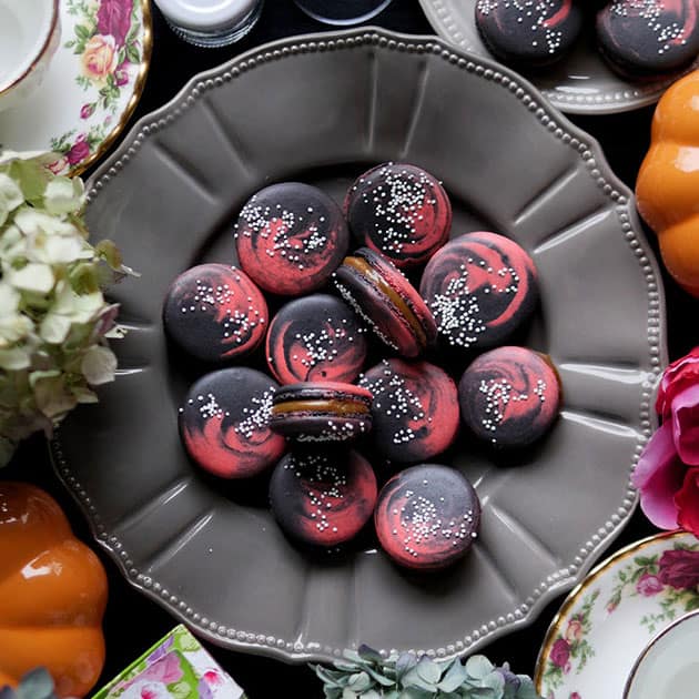 Close up of 2 color galaxy macarons on a plate.