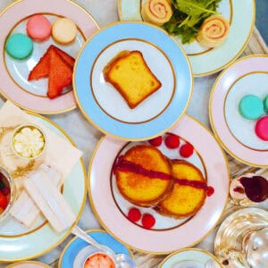 A bird's eye view of pastel colored afternoon tea ware with Laduree's iconic macarons and other Parisian treats.