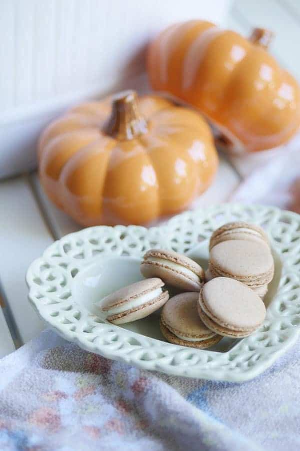 Pumpkin spice cheesecake macarons on a heart shaped plate.