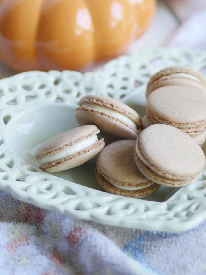 Pumpkin spice macarons on a heart shaped plate with pumpkin