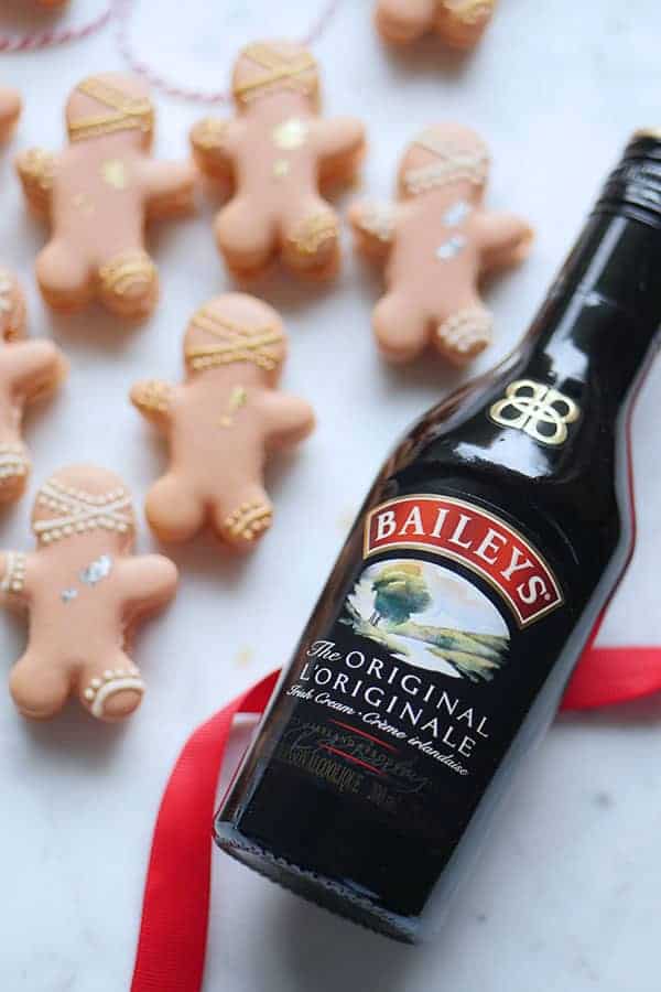 Close up of Baileys liqueur bottle with gingerbread man macarons in the back. 