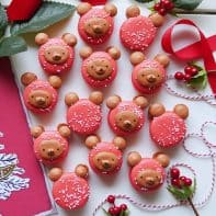 Christmas bear macarons with a holiday greeting card and holly on a white background.