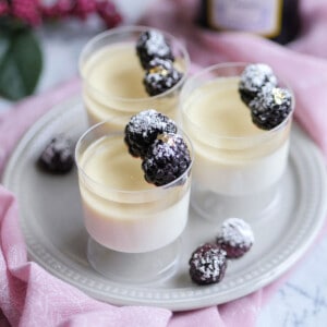 Champagne panna cotta in mini cups adorned with berries dusted with sugar.