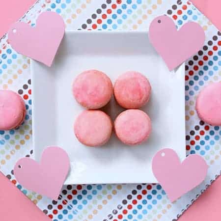 Marbled pink macarons on a plate adorned by hearts. 