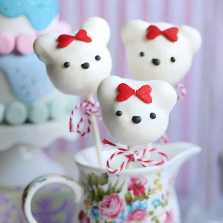Close up of donut hole cake pop bears propped inside a cup.