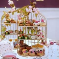 Afternoon tea treats displayed in a bird's cage display.