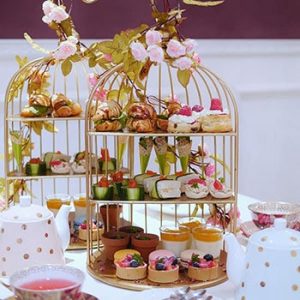 Afternoon tea treats displayed in a bird's cage display. 