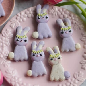 5 Easter bunny macarons on a floral plate.