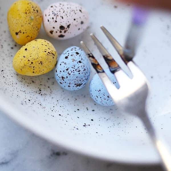 Fork splattering edible ink on easter eggs. 