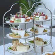High afternoon tea items served on a sleek white 3 tiered tea tray.