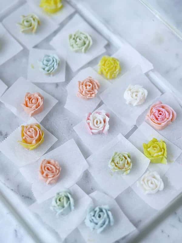 Buttercream piped into rose shapes on parchment paper. 