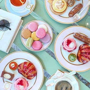Macarons, croissants, lemon meringues and more served on pastel tea ware.