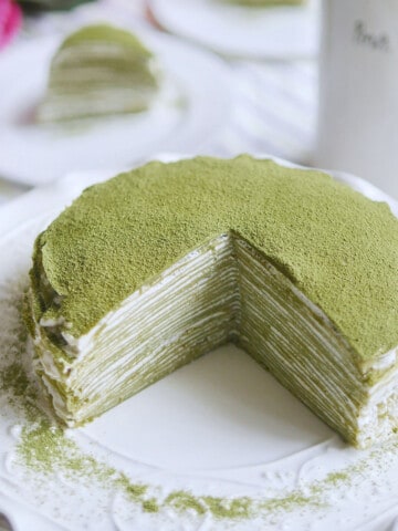 Beautiful matcha green crepe cake with a slice cut out.