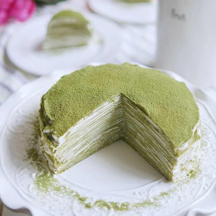 Beautiful matcha green crepe cake with a slice cut out.