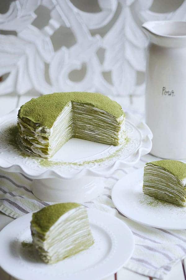 A whole matcha mille crepe cake cut open with 2 slices on the side. 