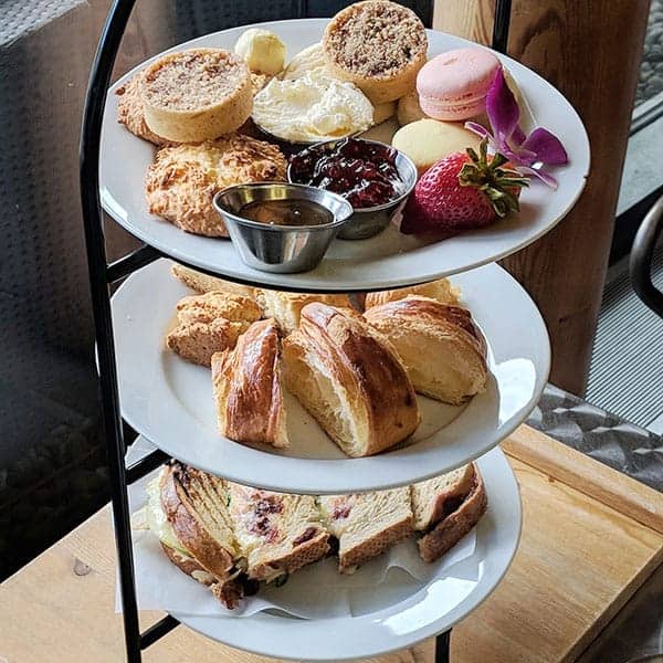 A 3-tier afternoon tea tray set on a table with desserts and treats.