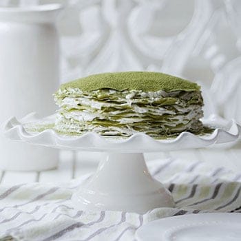 Side profile of a matcha crepe cake on a cake stand.