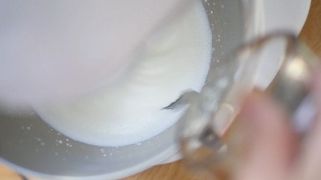 Pouring gelatin into whipped cream that is whipping in a stand mixer.