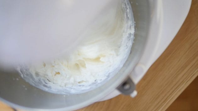 Whipped cream clumping inside mixing bowl.