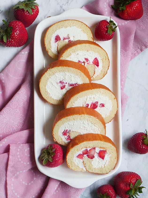 A bird's eye view of a strawberry Japanese cake roll cut up into 6 slices.