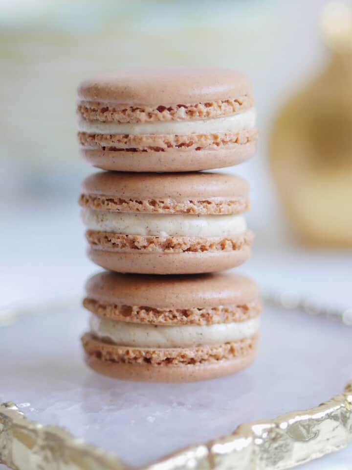 A stack of 3 gingerbread spice macarons on an agate plate.