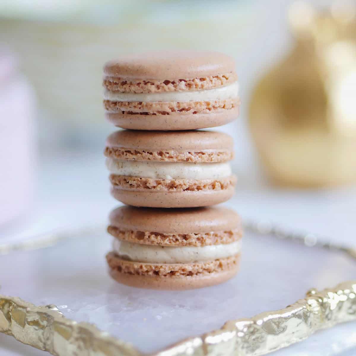A stack of 3 gingerbread spice macarons on an agate plate.