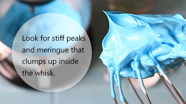 A ballon whisk with blue meringue clumped inside. 