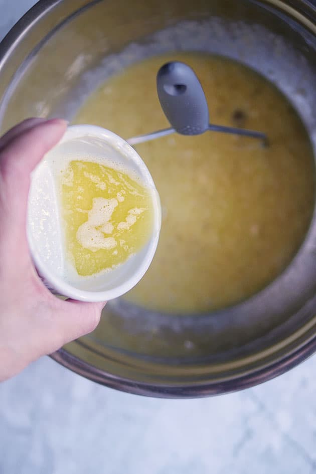 Melted butter being poured into  muffin batter in bowl. 