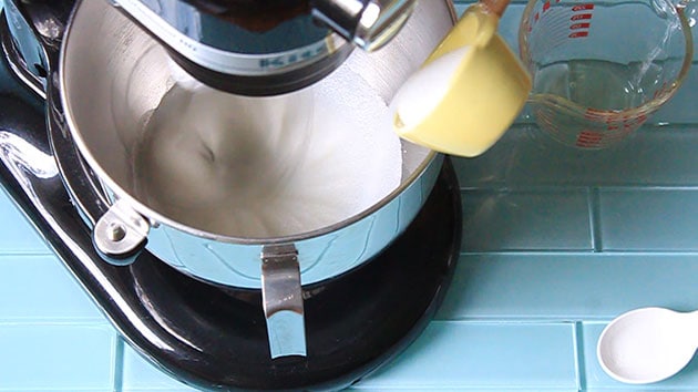 Egg whites being whipped with sugar being added.