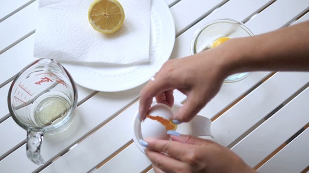 An egg is being opened in into an egg separator. 