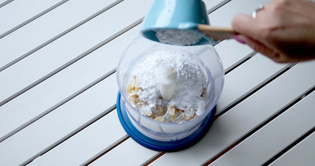 Pouring powdered sugar into a food processor. 