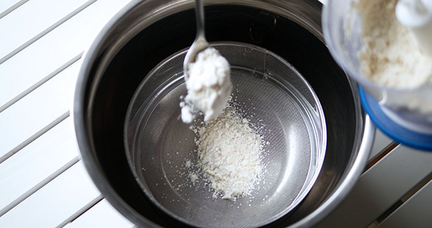 Sifting almond flour through a sieve. 