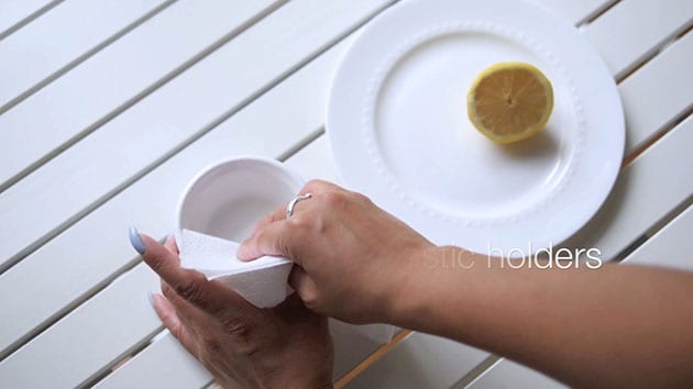 Hand is wiping clean the bowl with a paper towel. 