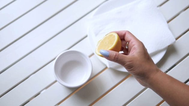 Hand is squeezing lemon into a bowl. 