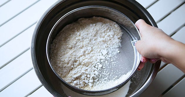 Sifting almond flour and powdered sugar mixture.