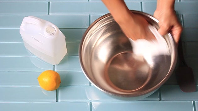 Wiping down a stainless steel bowl with lemon juice. 