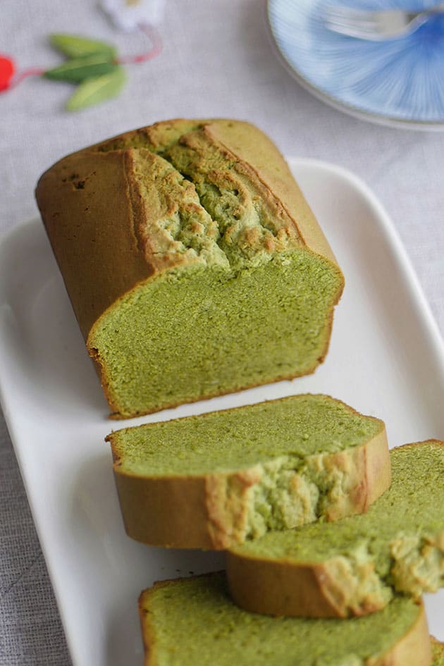 The end piece of matcha cake loaf shown cut open with a few slices in front of it. 