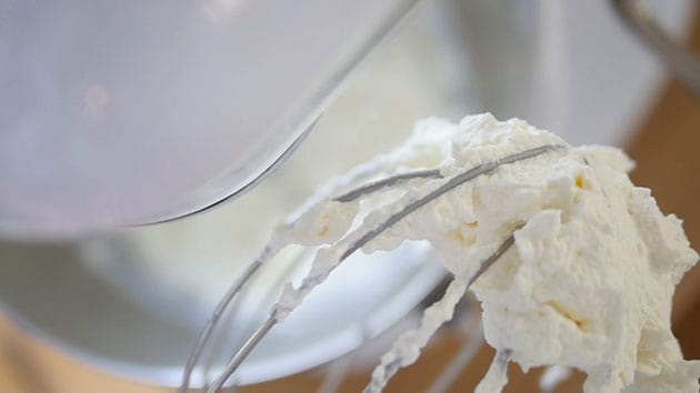 Close up of whipped cream clumped inside a balloon whisk.