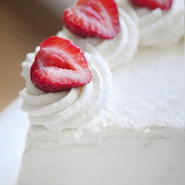 Close up of a swirl of whipped cream with a half open-faced strawberry on top. 