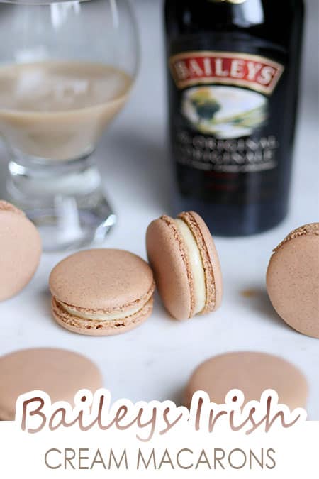 Baileys irish cream macarons with Baileys liqueur bottle in the back. 