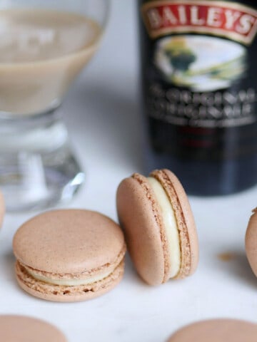 Baileys Irish Cream macarons with a bottle of coffee cream whisky in the back.