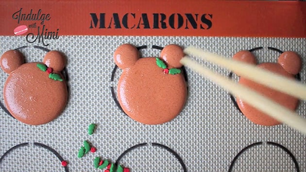 Christmas holly sprinkles added onto macaron bear batter. 