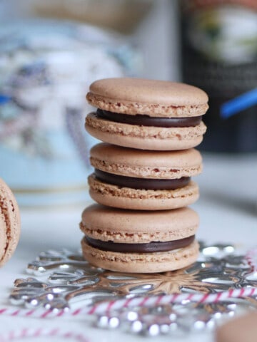 Close up of Baileys Chocolate Irish Cream macarons with a bottle of coffee cream in the back.