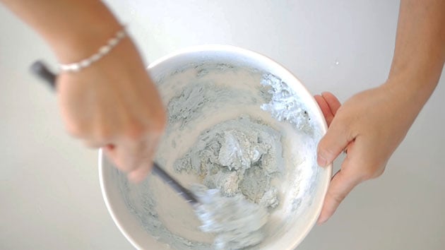 Folding macaron batter in a mixing bowl with spatula. 